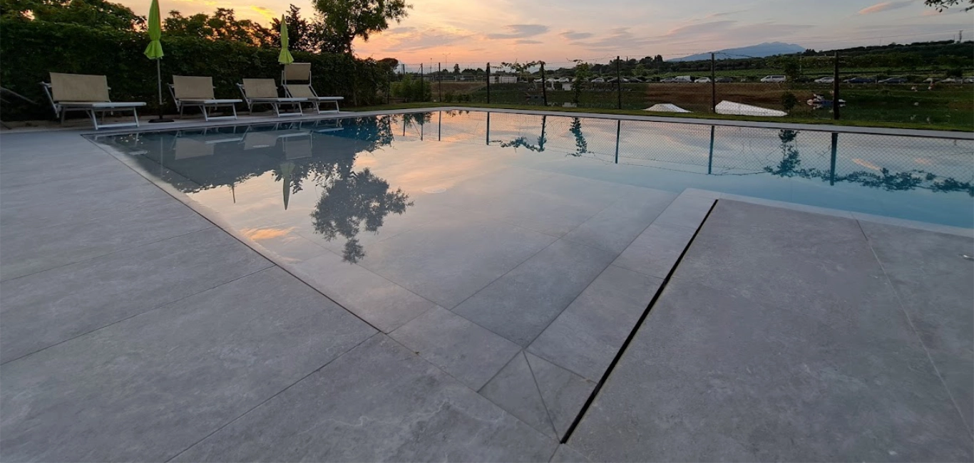 Piscina all'aperto al tramonto, sedie a sdraio