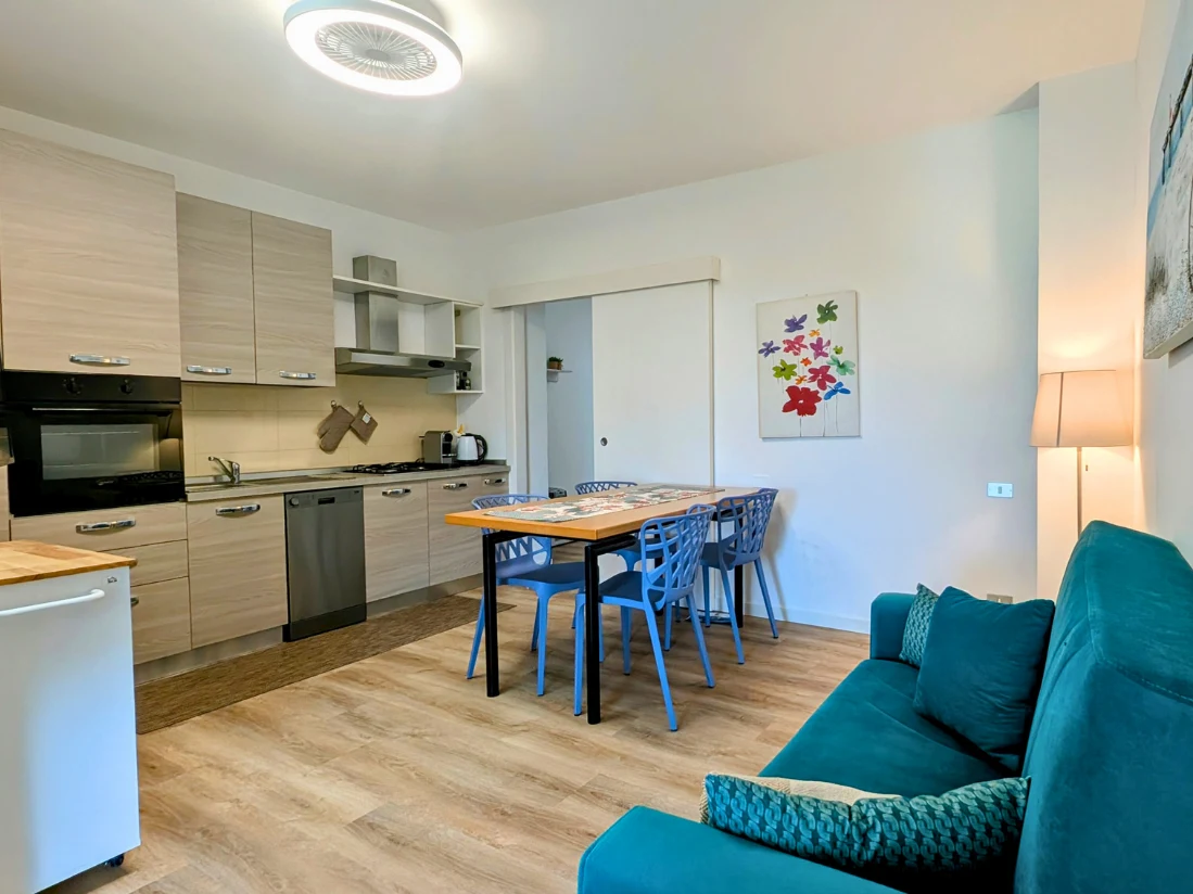 Cucina moderna con divano colorato e quadro floreale.